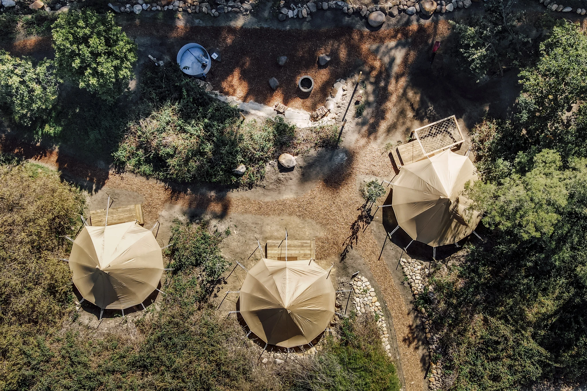 Overhead view of bell tents and a fire pit at De Stilte