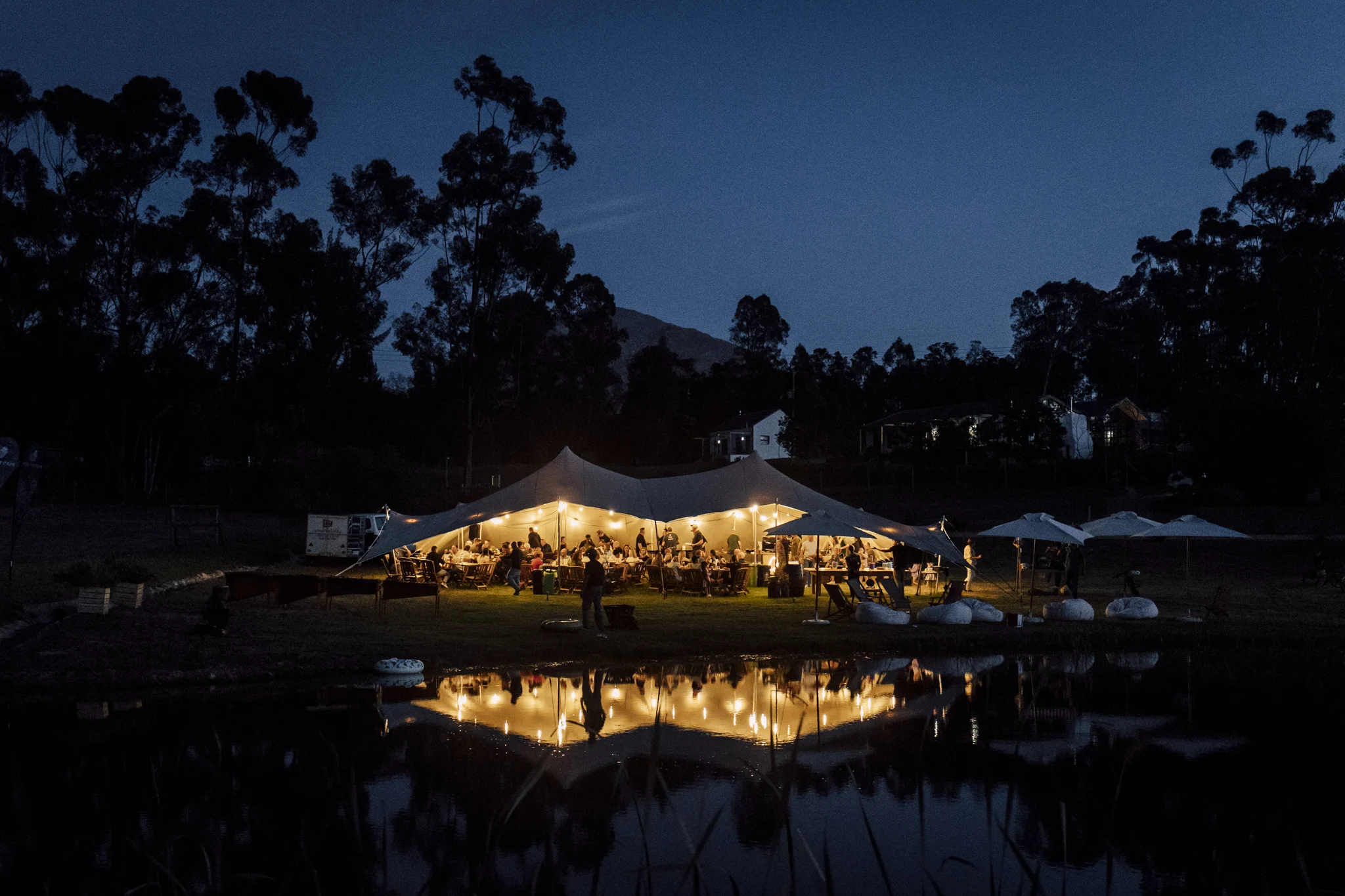 Illuminated reception tent reflected in the dam after dark